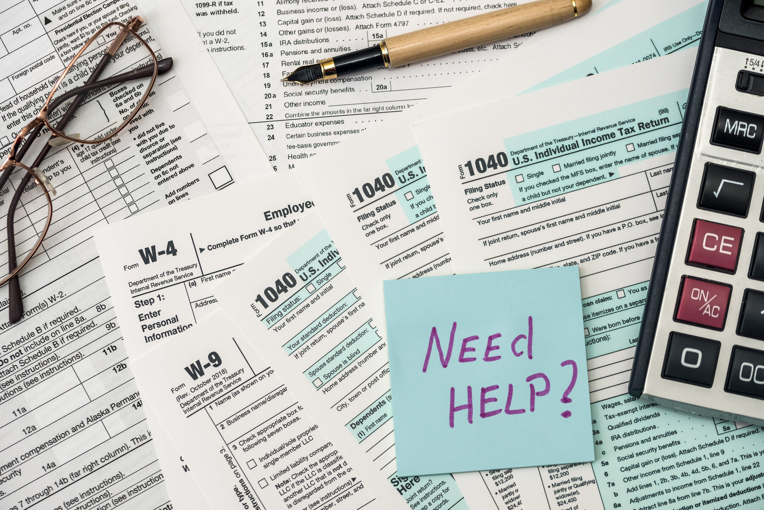 1040 tax form in office with need help text A group of people sitting at computers reading over documents